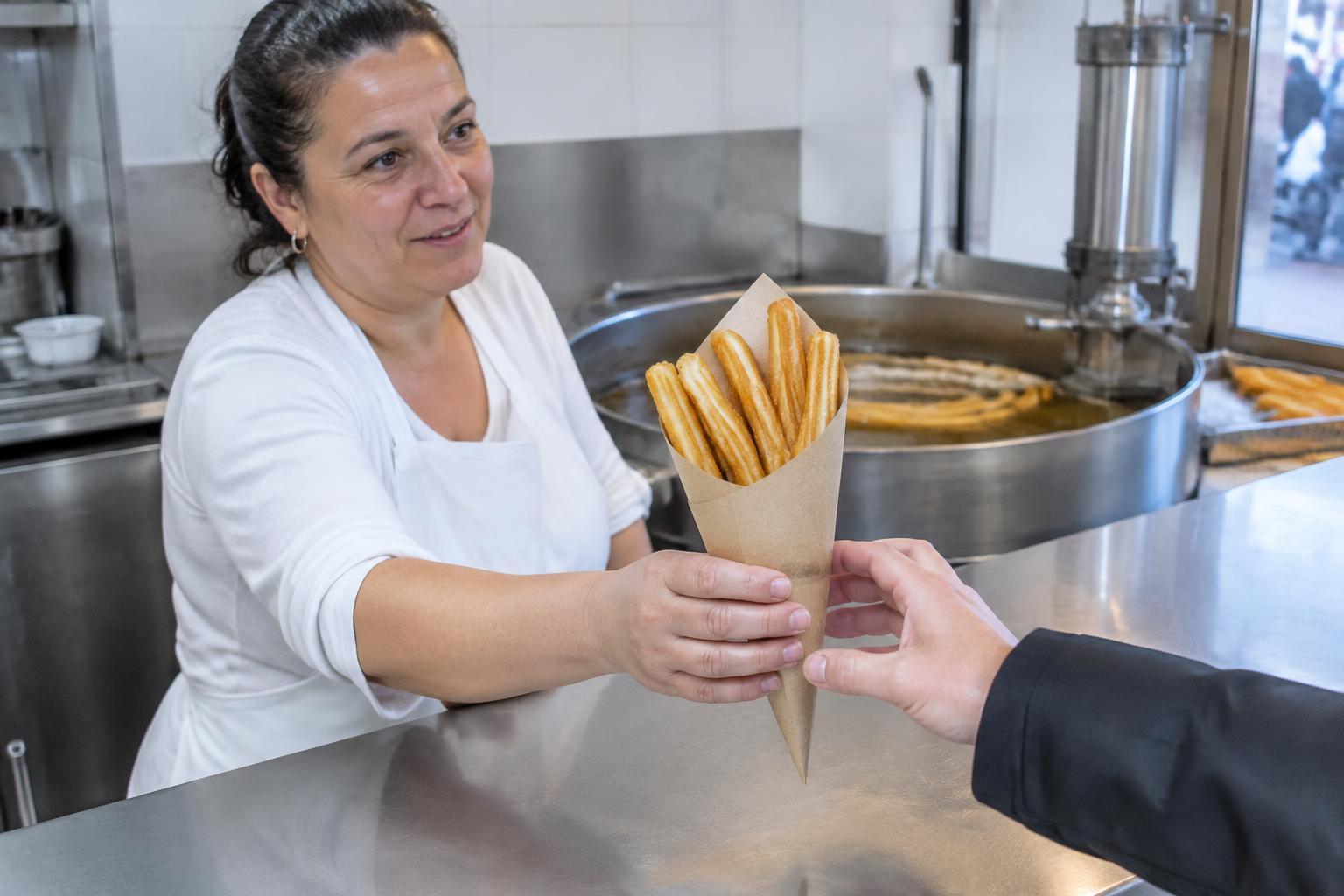 Fotografía de apoyo: atención cercana entregando churros en una churrería